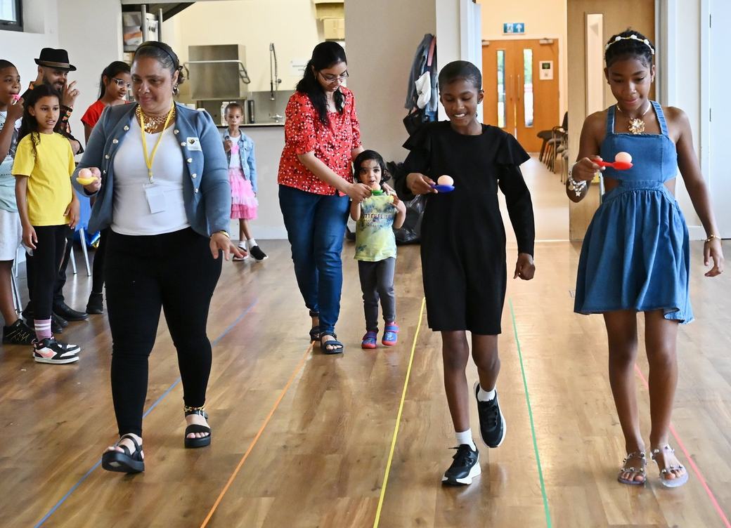 Children walking in an egg and spoon activity across the hall