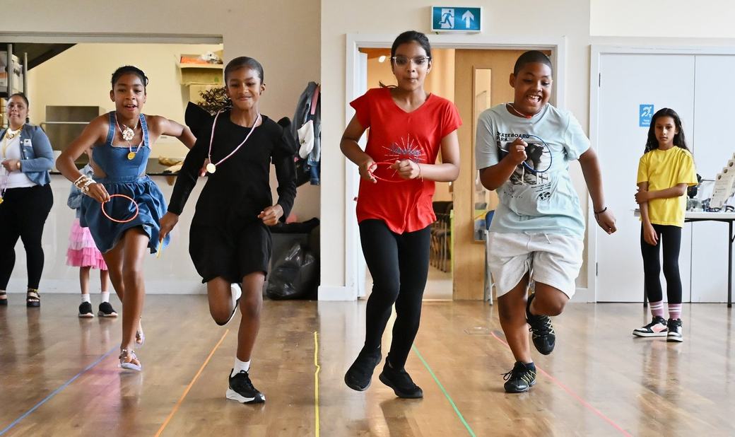 Children running together across the community hall